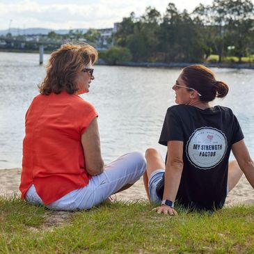 Support worker and client sitting on the grass talking
