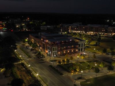 A nighttime aerial view of a lit urban area with streets and buildings.