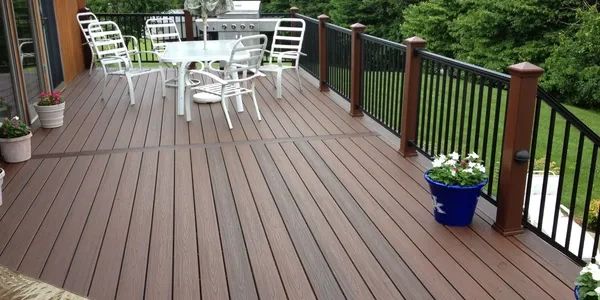 Spacious outdoor deck with white chairs and a blue flower pot.