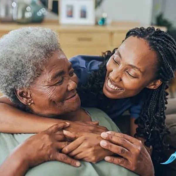 A loving younger woman embraces an elderly woman, sharing a warm, joyful moment.