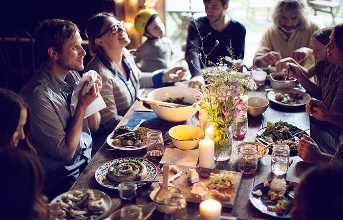 A group of young men and women and a child sharing a meal and laughing.