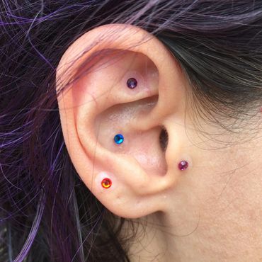 Colored crystal ear seeds on a woman's ear.