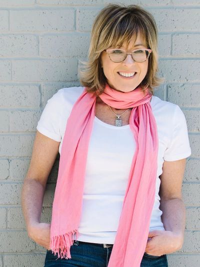 Jackie of Dynamic Downsizing leaning against brick wall