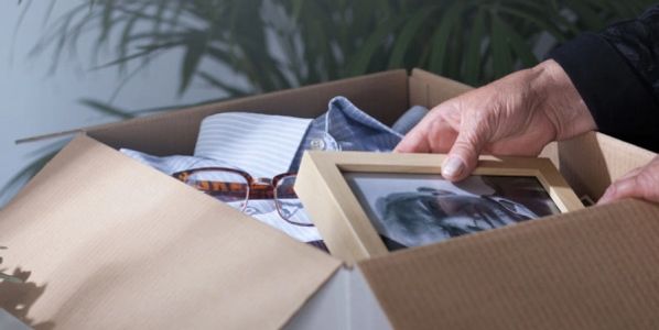 Old person's hand packing mementos in box