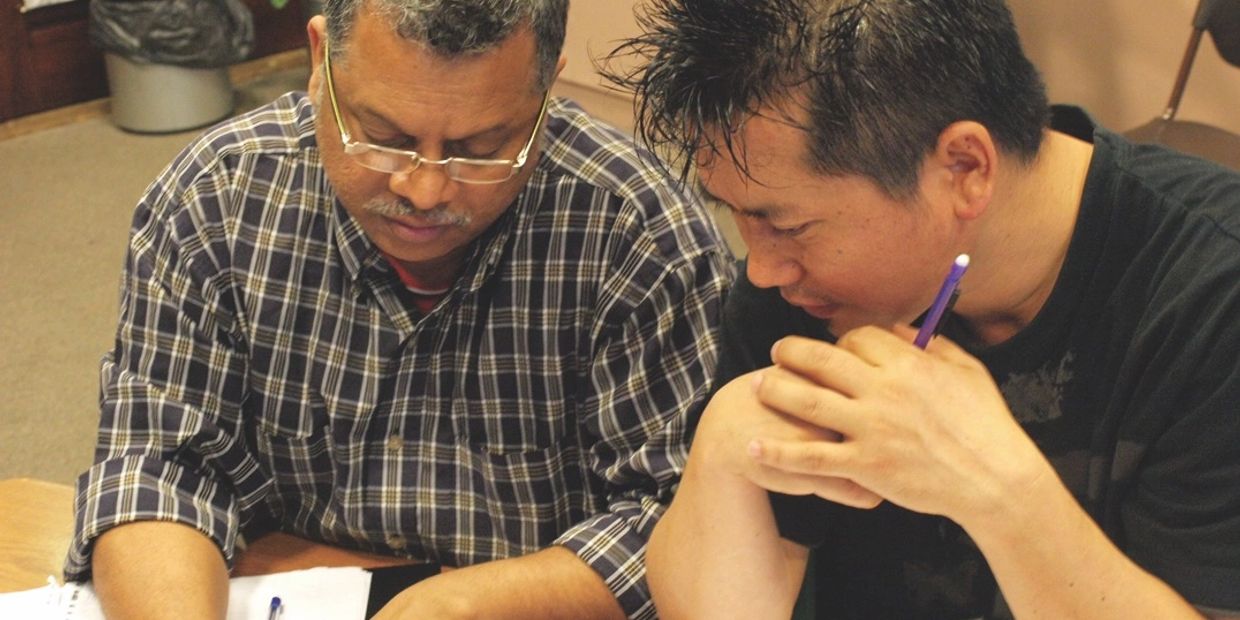 Two men collaborating and writing at a table.