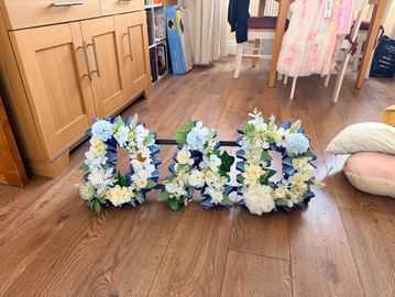 Floral letters spelling "DAD" on a wooden floor.