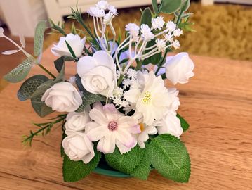 Arrangement of white artificial flowers in a green pot.