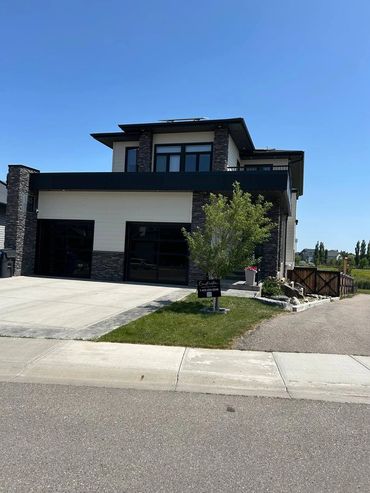 Modern two-story house with stone and white exterior under clear blue sky.