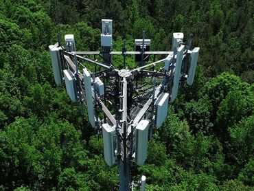 Top view of a cell tower surrounded by dense green forest.