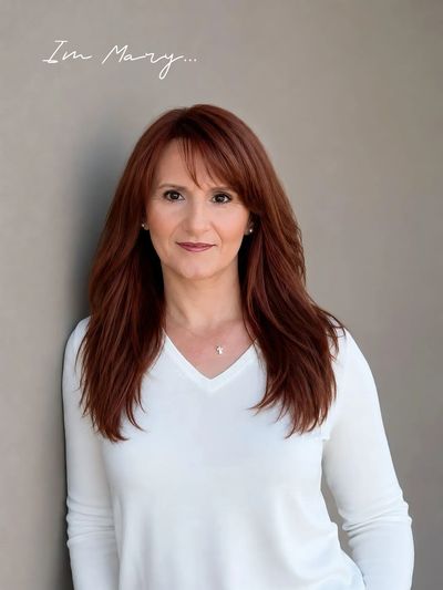 Portrait of a woman named Mary with long red hair and a white top.