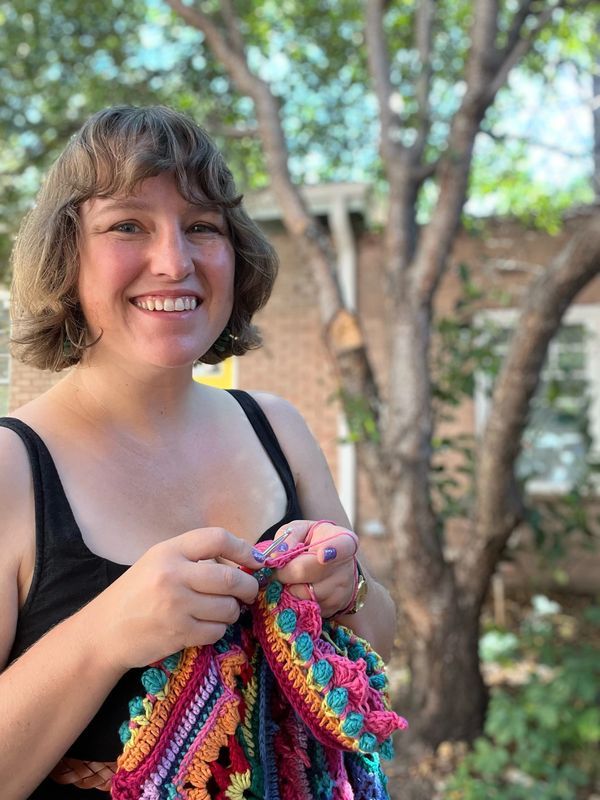 Dietitian nutritionist, Jule ODonovan knitting outdoors wearing a black top.