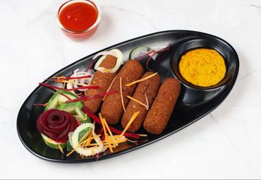 Plate of fried kebabs with sauces and vegetable garnish.