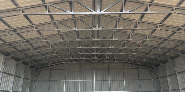 Interior view of a large empty metal warehouse with a high ceiling.