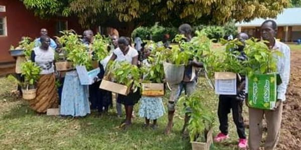 Group of people holding young plants in containers outdoors.