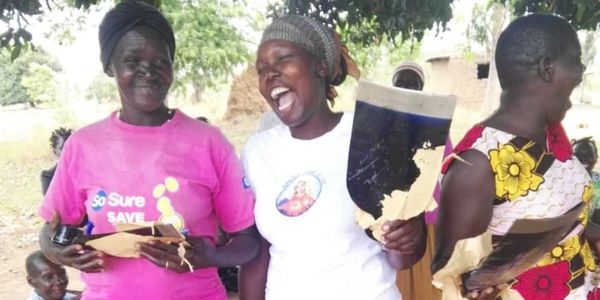 Three women joyfully holding torn ID cards outdoors.