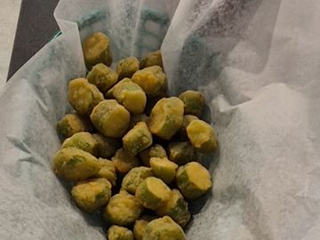Basket of fried okra served on white parchment paper.