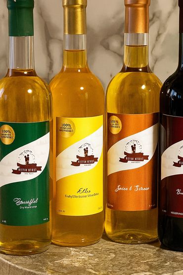 Four bottles of wine with colorful labels and foil caps on a marble background.