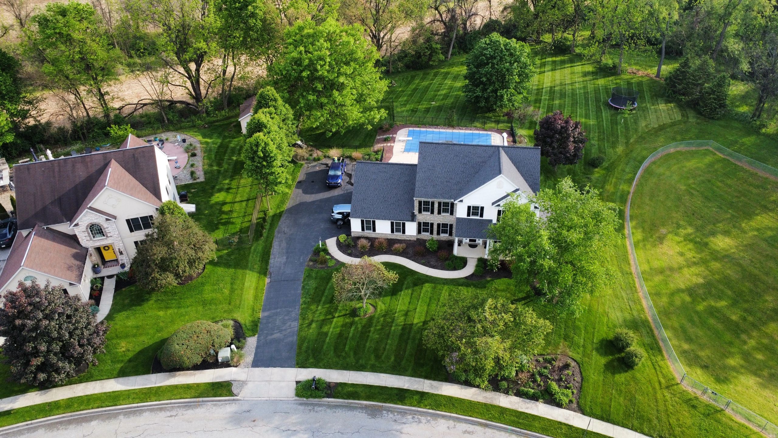 Aerial view of suburban houses with well-maintained lawns and a swimming pool.