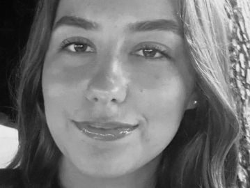 Close-up of a smiling young woman in black and white.