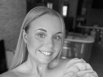 Smiling young woman taking a black-and-white selfie indoors.