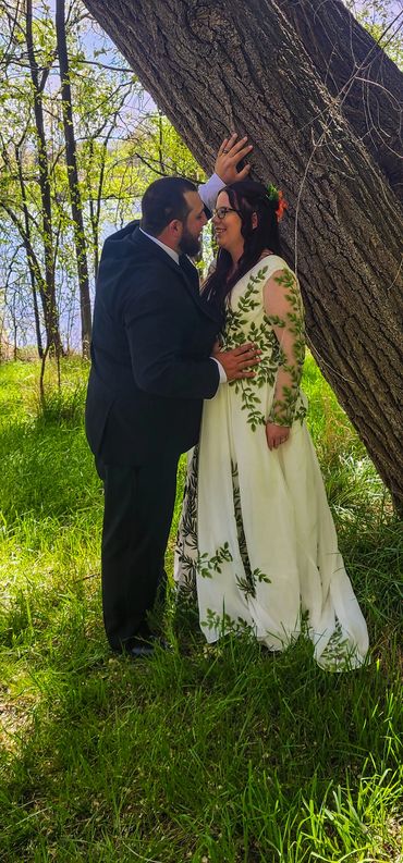 A groom places his hand upon his bride's waist and leans in for a kiss with his hand placed above he