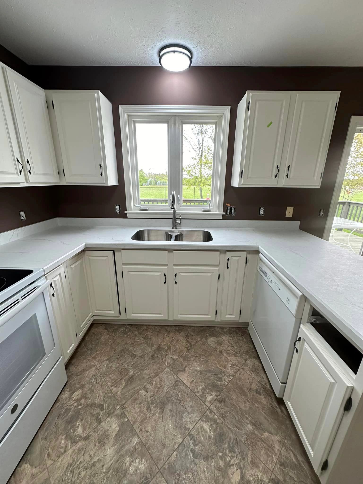 Modern kitchen with white cabinets and marble countertops.
