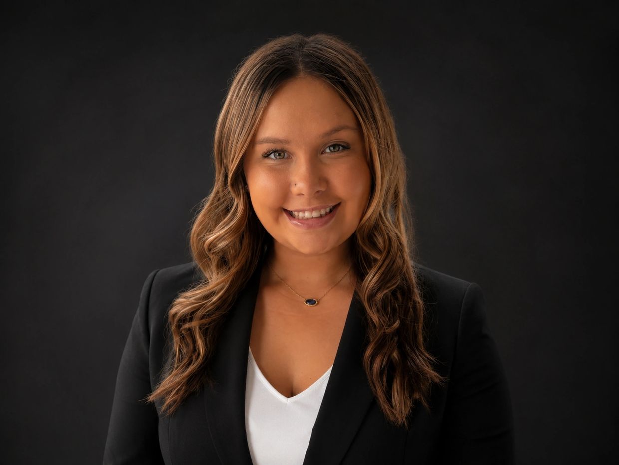 Professional woman smiling against black backdrop.