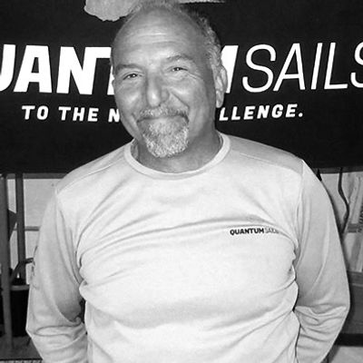 Smiling man posing in front of a Quantum Sails banner.