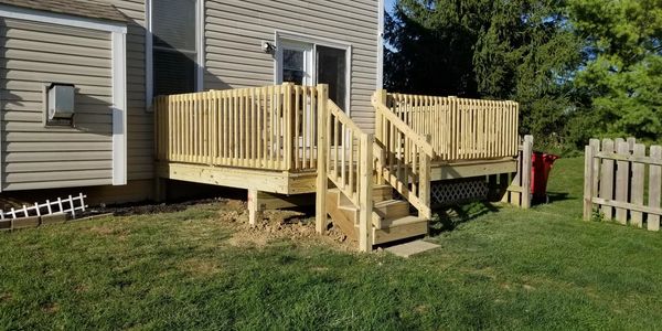 Newly built wooden deck with stairs attached to a house.