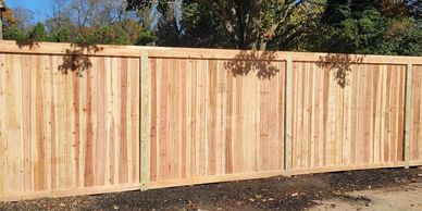 A six foot tall cedar cap and trim privacy fence with treated wood posts