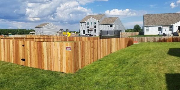 A four foot tall Cedar wood privacy fence with a gate in a suburban neighborhood on a sunny day