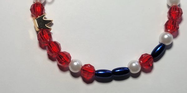 Beaded bracelet with red, white, blue beads, and a gold crown charm.