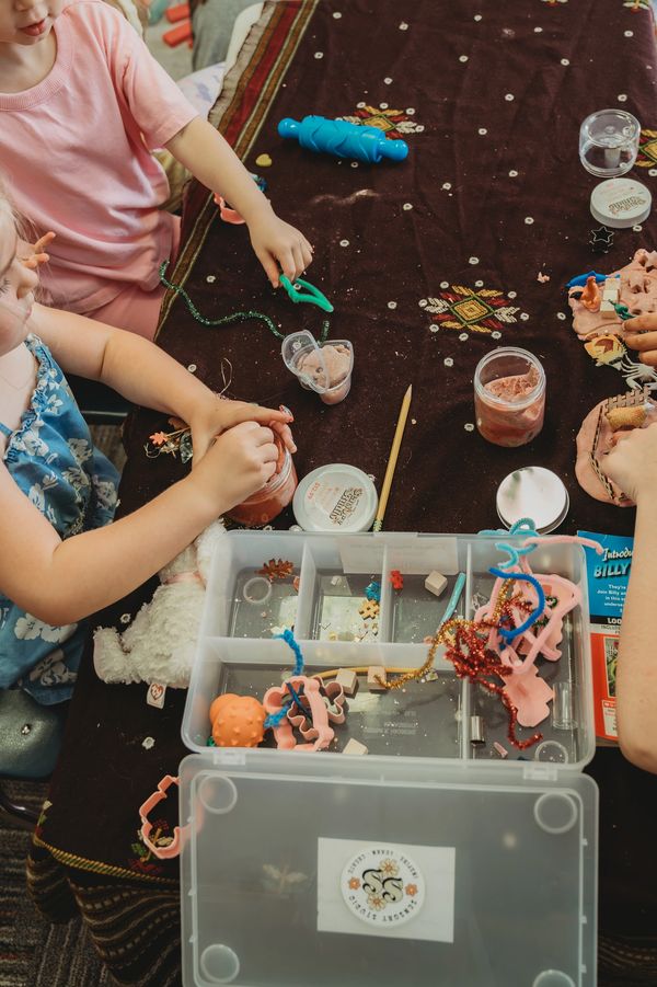Children playing with craft supplies on a table.