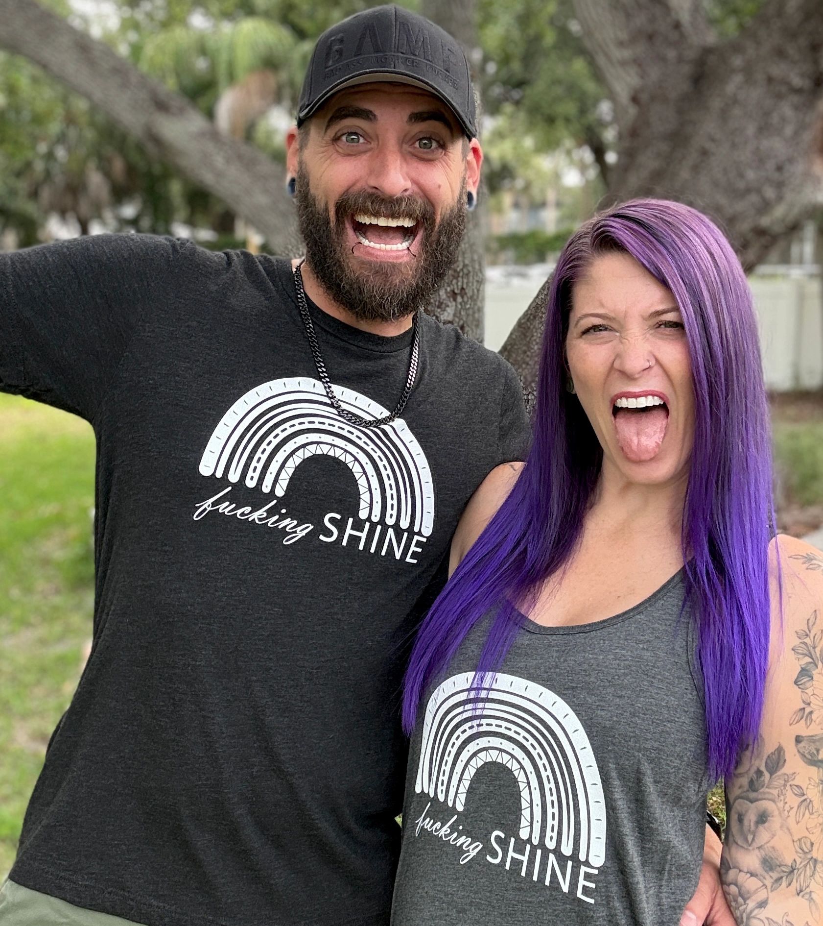 Man and woman with colorful hair making funny faces outdoors.