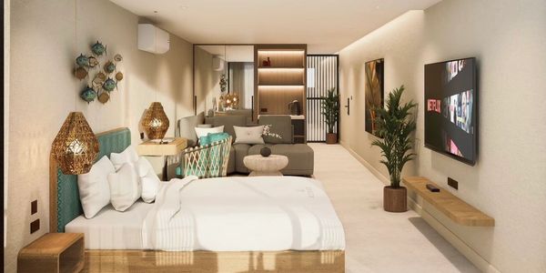 Modern hotel room with bed, sofa, and wall-mounted TV.