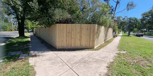 Newly installed wooden fence encloses a garden corner with greenery.