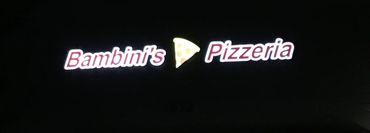 Illuminated sign of Bambini's Pizzeria with a pizza slice icon.