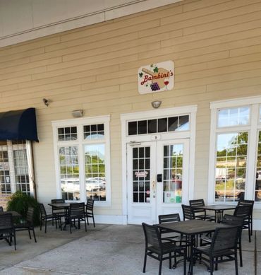 Outdoor seating area in front of Bambini's pizzeria with tables and chairs.