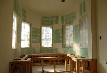 Room under construction with wooden framing and unfinished walls around windows.
