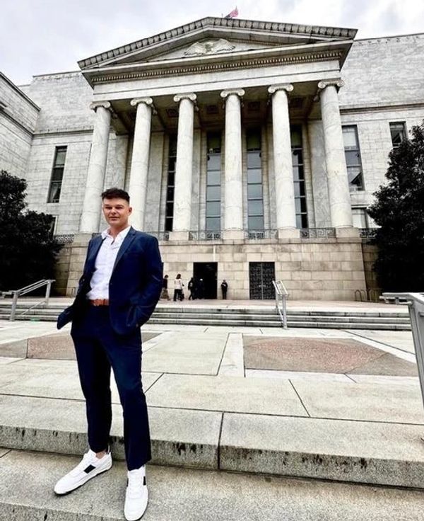 Man in a suit standing outside a neoclassical building.