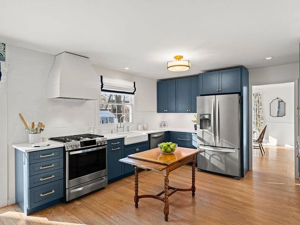 Kitchen cabinets Kraftmaid Harbor Blue with brass hardware a bell oven hood  and antique wood table