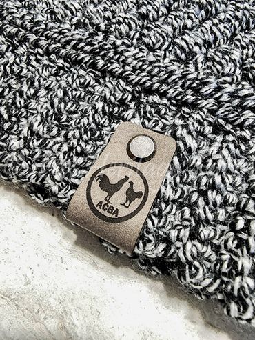 Close-up of a knitted fabric with a leather tag featuring a rooster and hen logo.