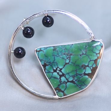 Sterling silver brooch features Spiderweb Turquoise and black onyx