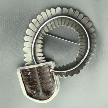 This sterling silver brooch features a  fossil fern of the genus  Neuropteris. 