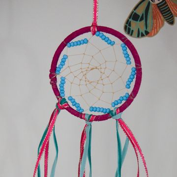 Handcrafted dreamcatcher with blue beads and colorful ribbons.