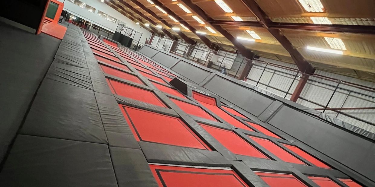 Indoor trampoline park with red and black trampolines.