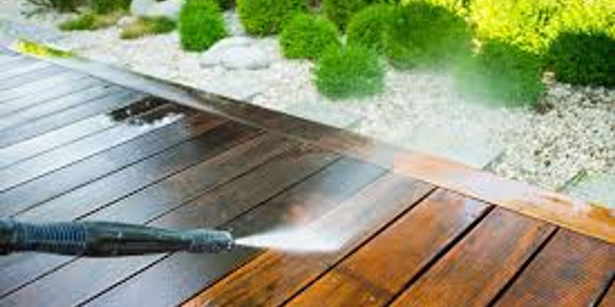 A pressure washer cleaning a wooden deck outdoors.