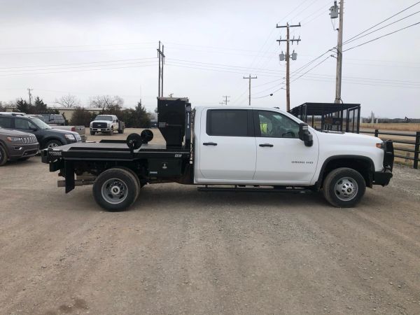 White flatbed truck parked on gravel road.