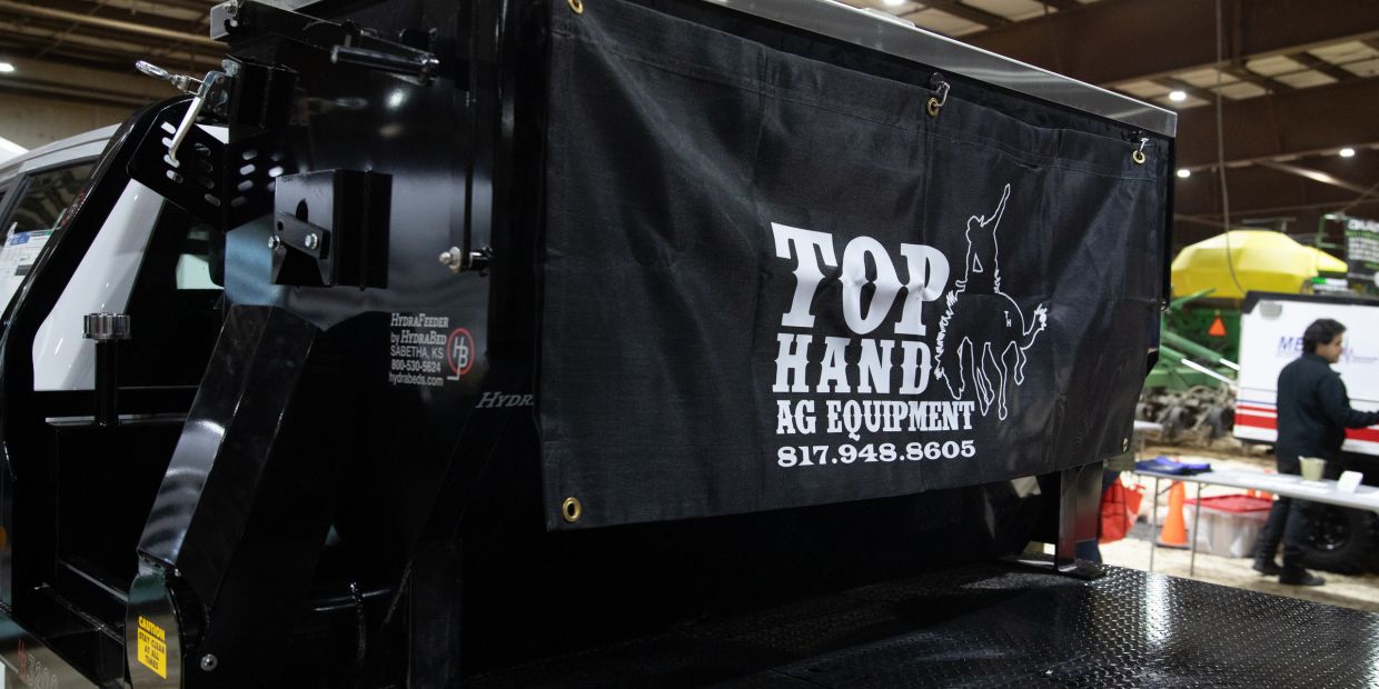 Banner on black agricultural equipment reads Top Hand AG Equipment with phone number.