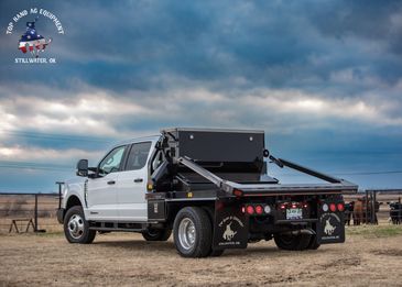 White flatbed truck with equipment on a rural field.